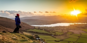 Sunset over Llangorse lake with man and dog on Mynydd Llangorse