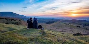 Couple sit at base of Hay Bluff looking out at the sunset